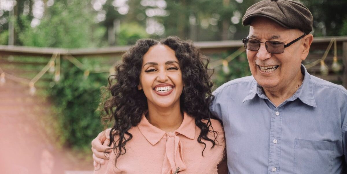 A woman and her father smiling at a party.