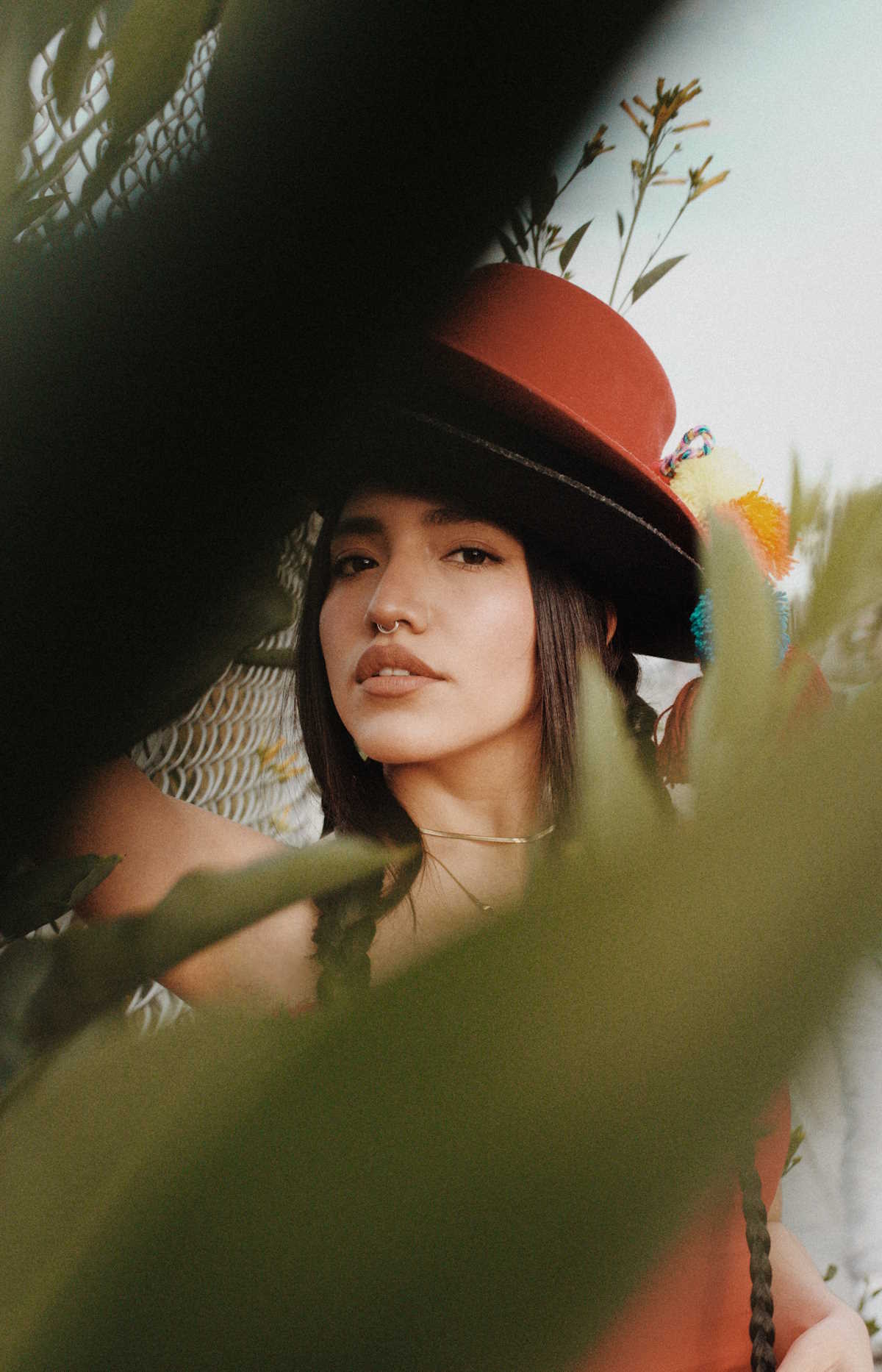 Image of Renata Flores, in focus, with an out-of-focus plant partially covering her in the foreground