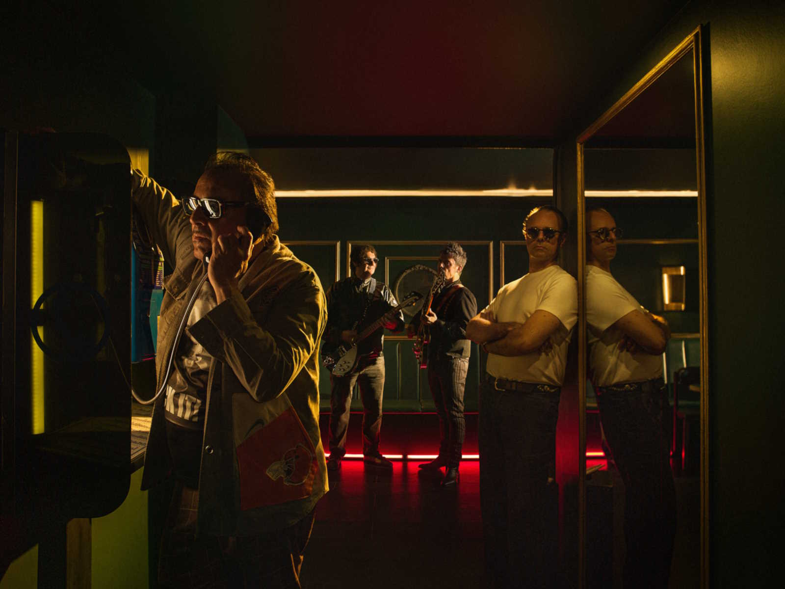 Promotional image of Los Tres. They are in a nightclub or bar. The image is dark and has a soft glow.